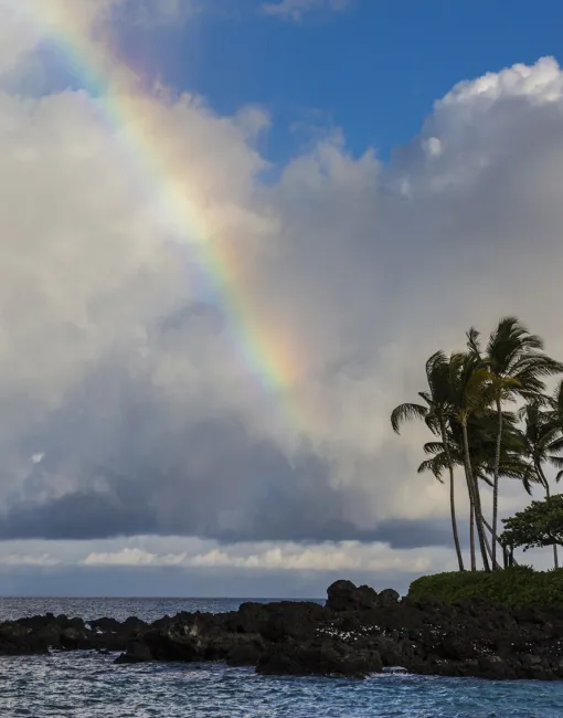 Rainbow cutting through a partly cloudy sky over the beach