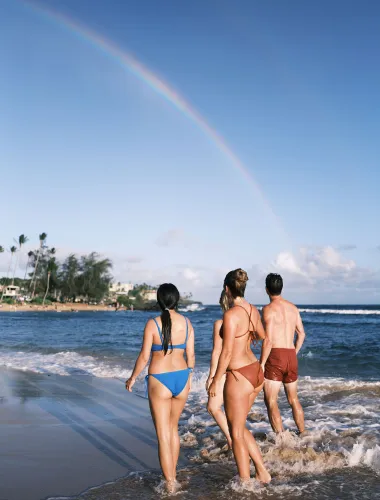 Beachgoers and rainbow at Poʻipū Beach on Kauaʻi in Hawaiʻi