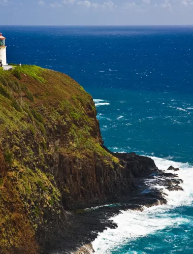 Lighthouse perched on a dramatic cliff overlooking the ocean with waves crashing below.