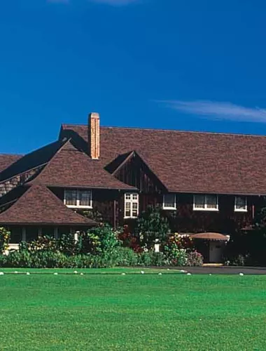 A large plantation-style building with lush green grass and blue skies.