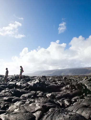 Frequently Asked Questions Visitors walking along a rocky coastal path under a clear blue sky.