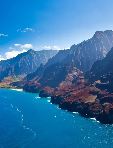 Stunning view of the Napali Coast with steep green cliffs meeting the blue ocean.