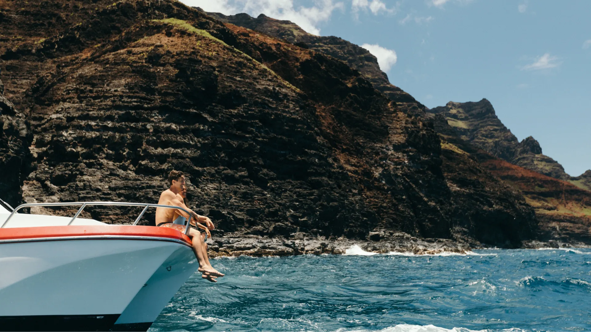 Couple approach Napali Coast on bow of tour boat