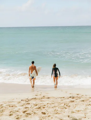 Couple heading out to surf at Kepuhi Beach on Molokaʻi in Hawaiʻi