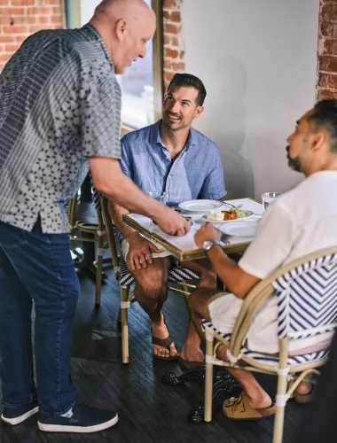 Waiter serves food to restaurant guests in Honolulu, Oʻahu, Hawaiʻi