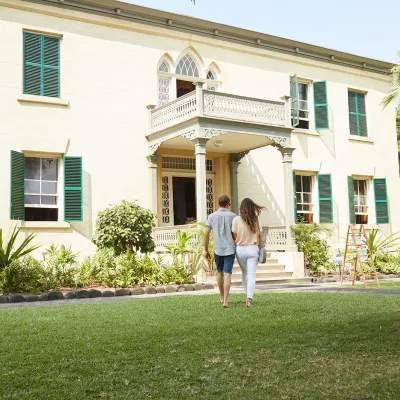 Historic Hulihee Palace, a white colonial-style building with a green lawn and palm trees in Kailua-Kona.