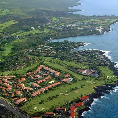 Aerial view of the Keauhou resort area, featuring lush green golf courses, homes, and the Pacific Ocean.