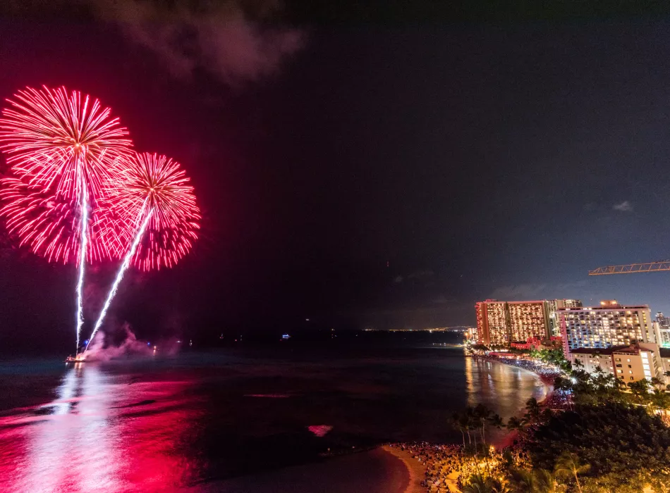 The beautiful fireworks bloom in the night sky over Waikiki Beach.