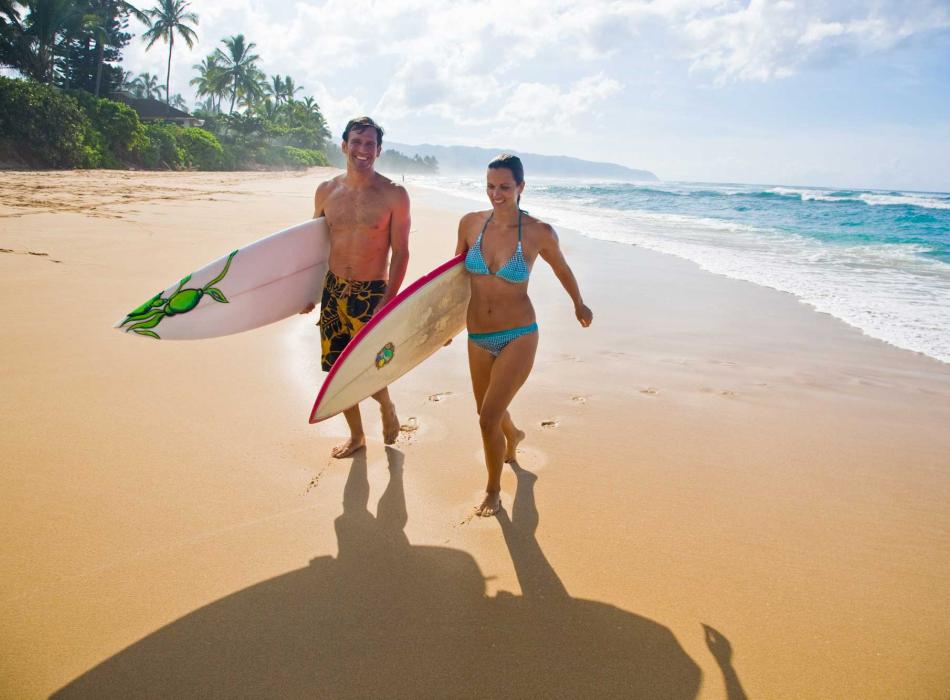 Couple with surfboards on a beach in Oahu