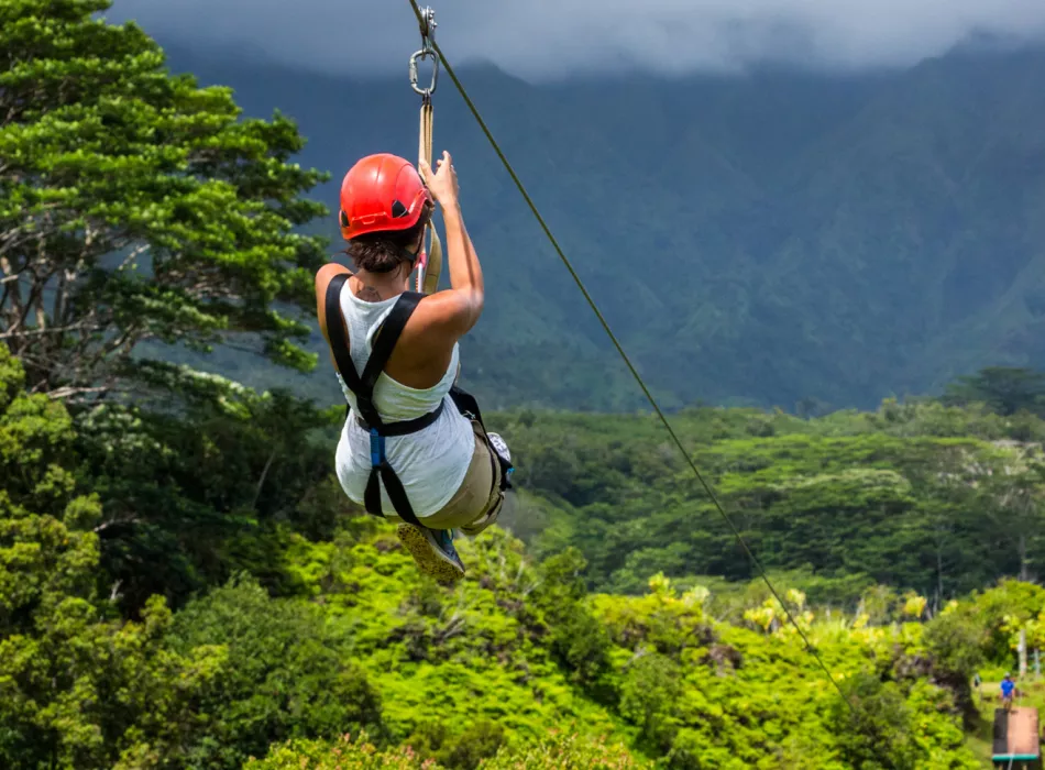 Person ziplining over lush greenery in Hawaii.