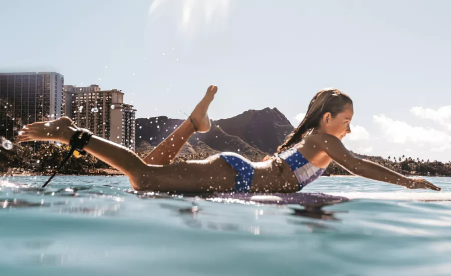 Young girl paddles out on a surfboard