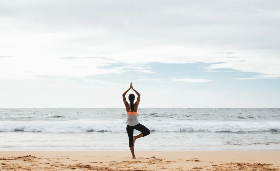 Woman practicing yoga on the beach