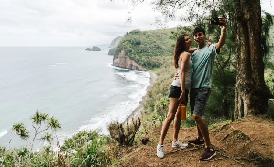 Couple look onto Pololu beach from hiking trail