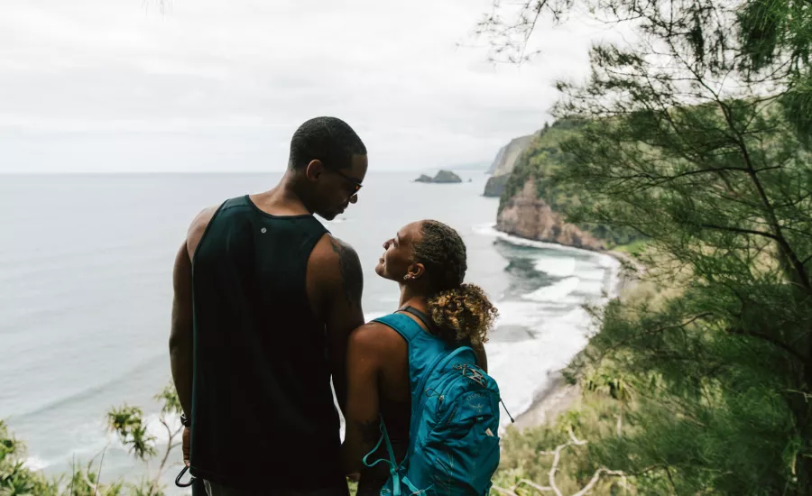 Couple look onto Pololu beach from hiking trail